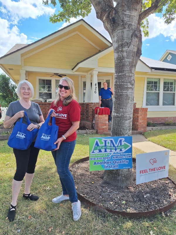 aim ac and heating services technician standing next to the lennox feel the love content winner in front of their house